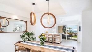 Een moderne eetruimte met een houten tafel en stoelen, een bloevas en hanglampen.