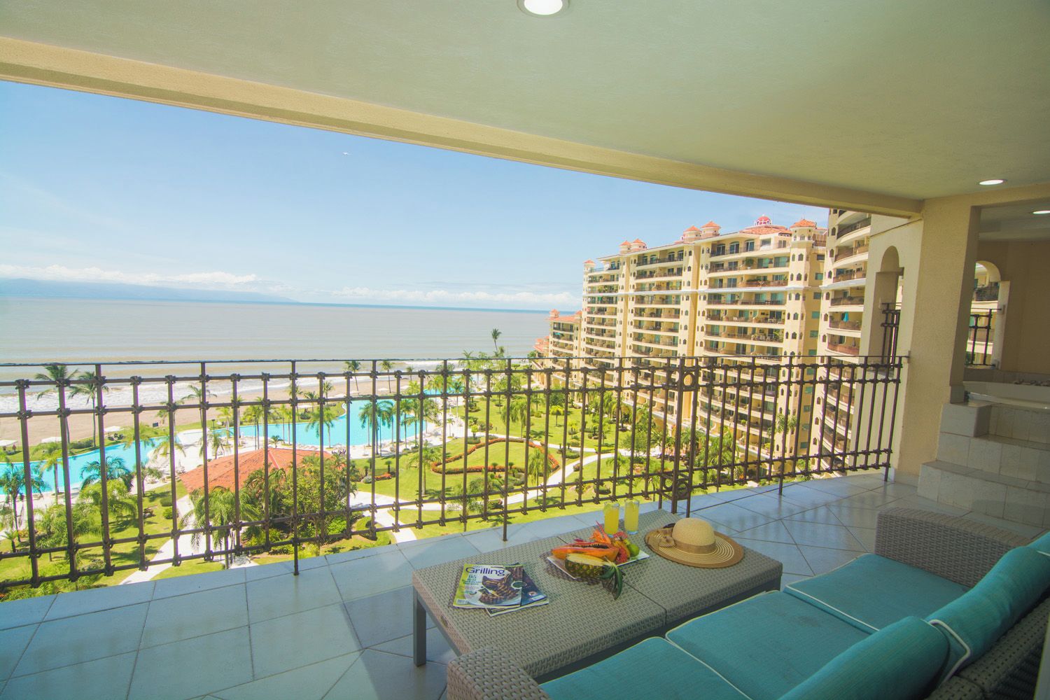 Un balcon avec vue sur une piscine d’hôtel, des palmiers et une plage.