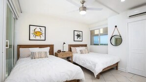 A bedroom with two beds, a ceiling fan, and framed artwork on the walls. - Beachfront condo best location spectacular views (Puerto Vallarta)