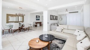 A spacious living room with a sofa, coffee table, dining area, and a large mirror. - Beachfront condo best location spectacular views (Puerto Vallarta)