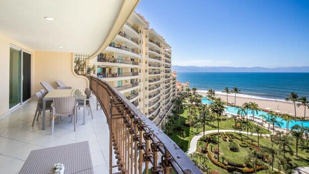 A balcony with a view of a beach and a pool. - Beachfront condo best location spectacular views (Puerto Vallarta)