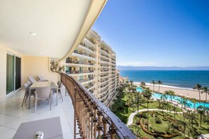 A balcony with a view of a beach and a pool. - Beachfront condo best location spectacular views (Puerto Vallarta)
