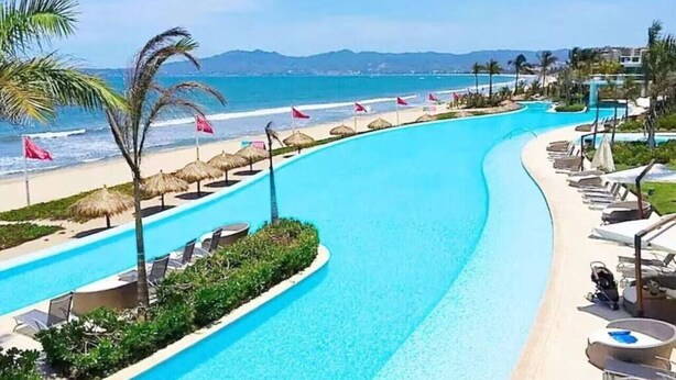 A pool with a view of the beach and mountains.