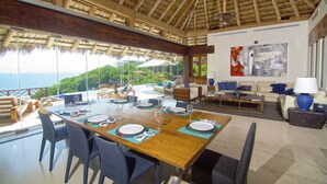 A dining area with a large table set for six, surrounded by chairs, with a view of the ocean and greenery. - Luxury staffed villa chef included-Punta Mita Corridor (La Cruz de Huanacaxtle)