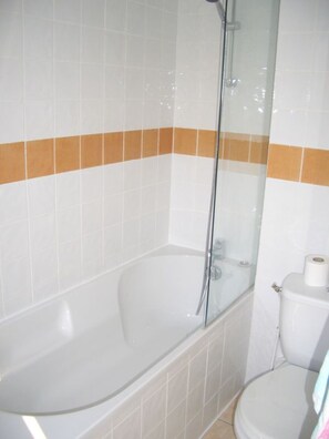 A bathroom with a bathtub, toilet, and glass shower enclosure.