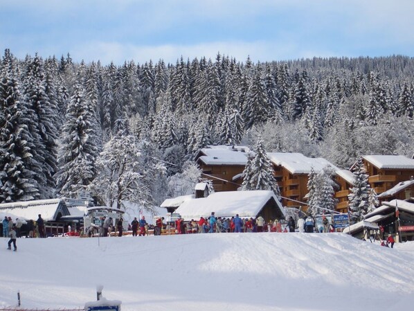 A ski resort with multiple wooden lodges, a ski lift, and a crowd of people.