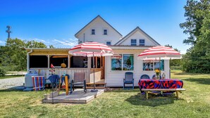 A house with a covered outdoor seating area, a table with a tablecloth, and a chair.