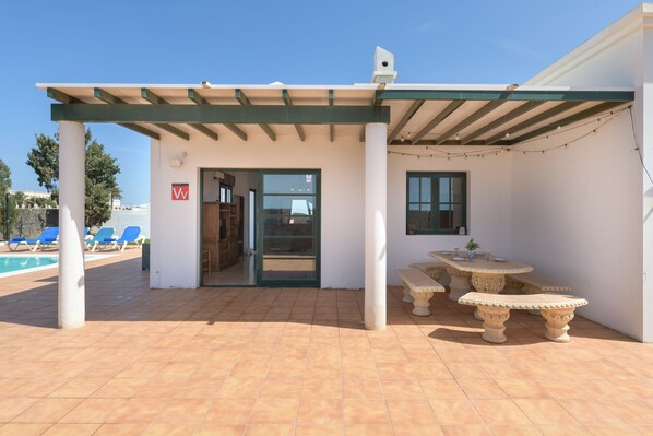 A covered outdoor area with a pool, a door, and a table with chairs.