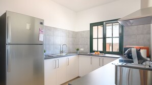 Una cocina moderna con un refrigerador de acero inoxidable, horno empotrado, lavamanos y ventana con vistas.