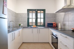 A modern kitchen with white cabinets, a double sink, a microwave, and a stove.
