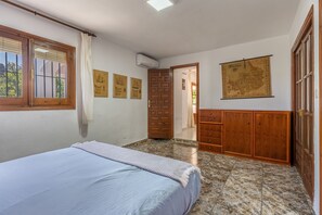 A bedroom with a bed, wooden wardrobe, a door, and a wall-mounted map.