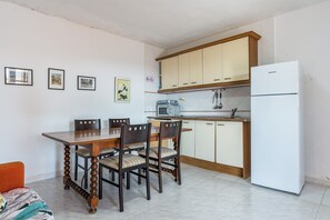 Una cocina con mesa, sillas, microondas y refrigerador.