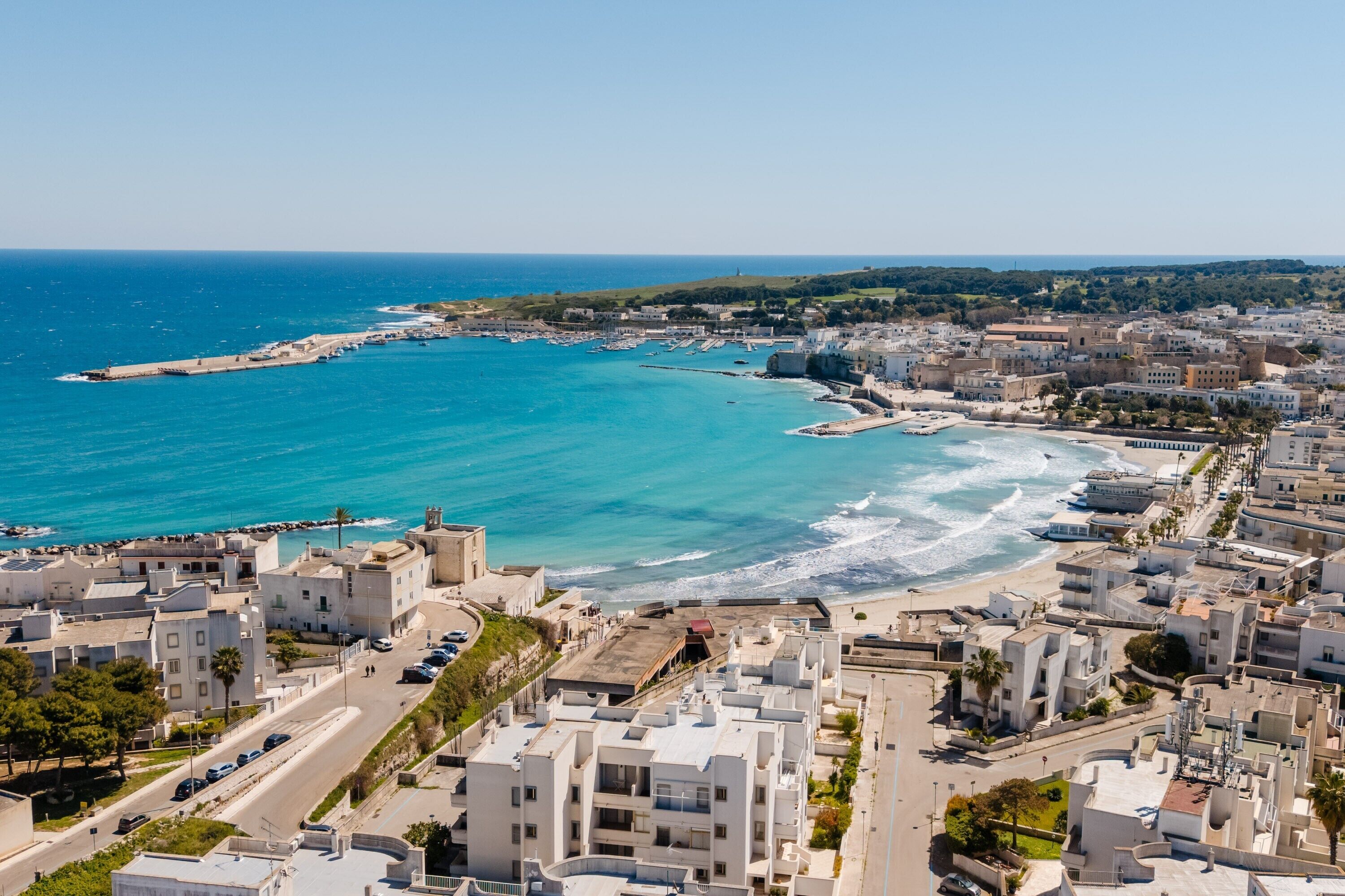 Una località costiera con edifici, una spiaggia e un porto turistico.