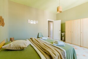 Une chambre à coucher comprenant un lit, une armoire, une chaise et un luminaire suspendu.