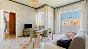 Un salon comprenant un canapé, une table à manger, des chaises et un téléviseur.