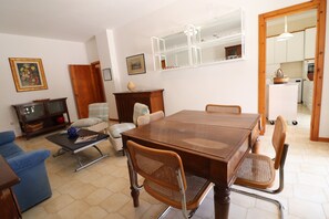 A dining area with a wooden table, chairs, a sofa, a cabinet, and a mirror.