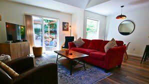 Un salon avec un canapé rouge, une table basse en bois et un téléviseur posé sur un meuble.