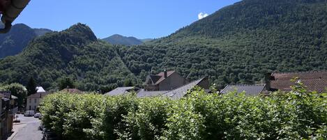 A residential street with houses, a mountain backdrop, and a clear sky.