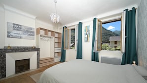 Une chambre à coucher avec un lit, une cheminée, une armoire et une fenêtre avec des rideaux.