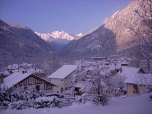 A snow-covered village with houses and mountains in the background.