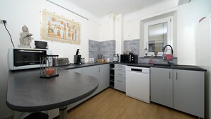 A modern kitchen with a round table, white cabinets, a microwave, and a coffee maker. - Guest House 'Jolie Chambre Au Calme À Auzat' with Mountain View (Auzat)