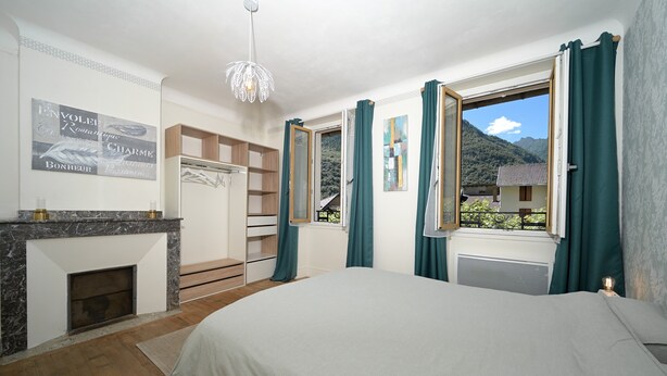 A bedroom with a bed, a fireplace, a wardrobe, and a window with curtains. - Guest House 'Jolie Chambre Au Calme À Auzat' with Mountain View (Auzat)