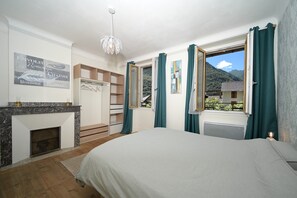 A bedroom with a bed, a fireplace, a wardrobe, and a window with curtains.