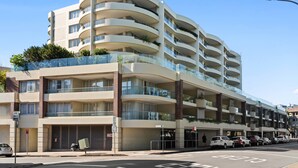 A multi-story hotel with balconies, a parking area, and a clear sky. - Manly Seabreeze With 1 Bathrooms (Manly)