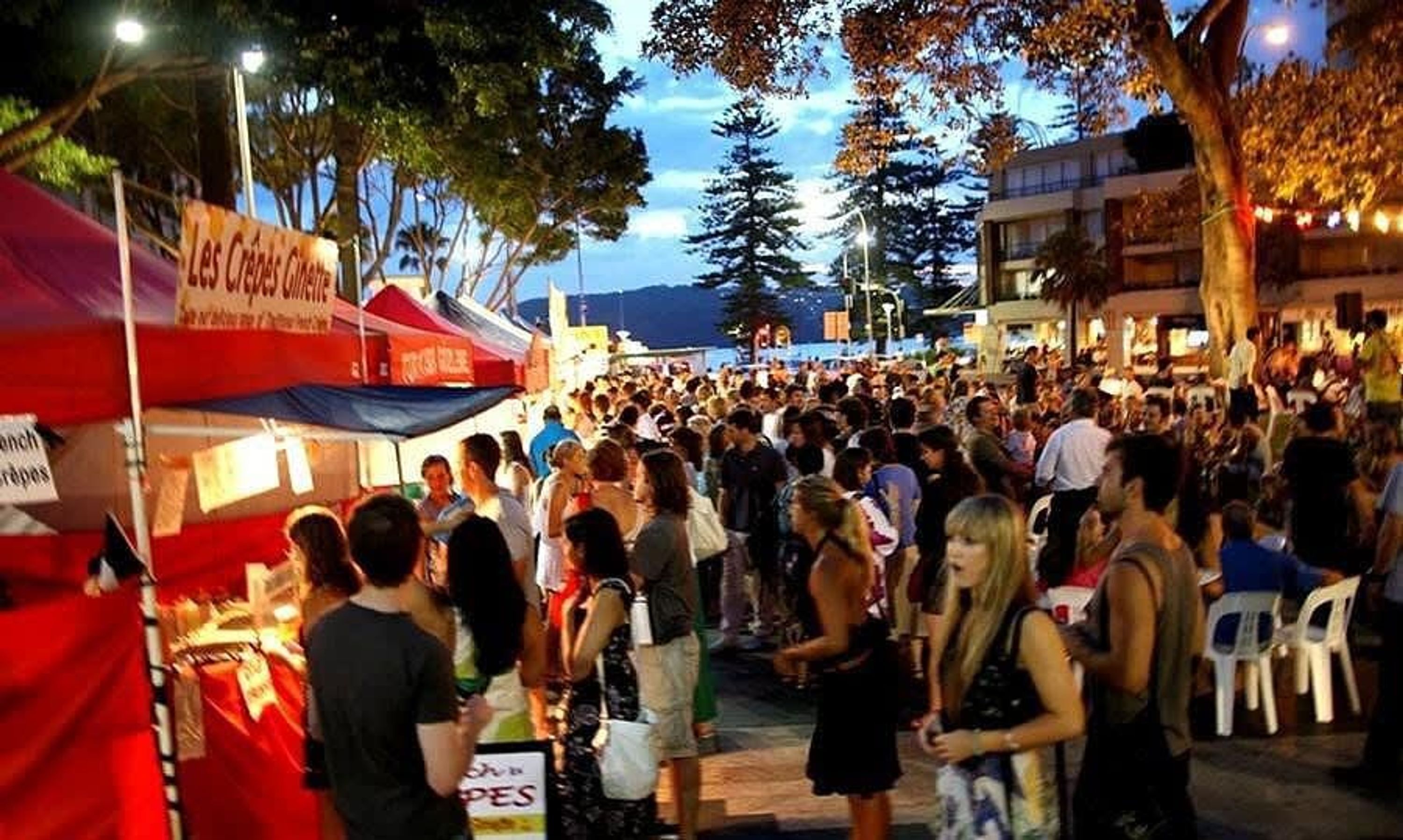 Un mercado al aire libre concurrido, con varios puestos y gente.