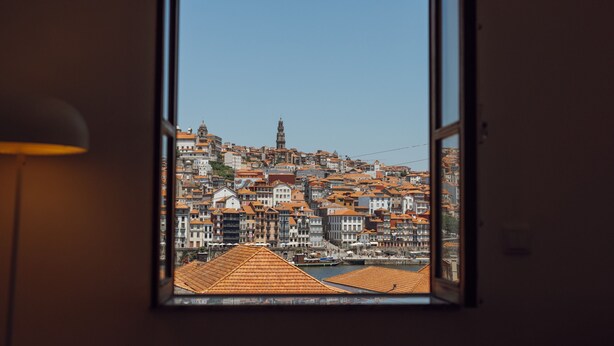 A view through a window of a cityscape with buildings and a prominent tower. - Douro Panoramic Views by Vacationy (Vila Nova de Gaia)