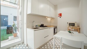 A compact kitchen with a sink, stove, and microwave, a small dining table, and a potted plant. - Douro Panoramic Views by Vacationy (Vila Nova de Gaia)