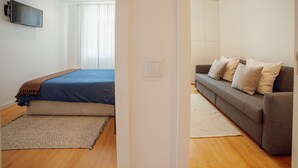 A modern bedroom with a bed, a sofa, and a TV. - Douro Panoramic Views by Vacationy (Vila Nova de Gaia)