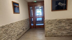 Un pasillo con paredes de piedra, suelo de baldosas y puerta de madera.