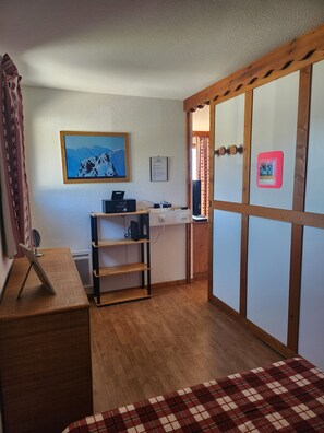 Une pièce avec un bureau en bois, une étagère, un tableau accroché au mur et une porte coulissante.
