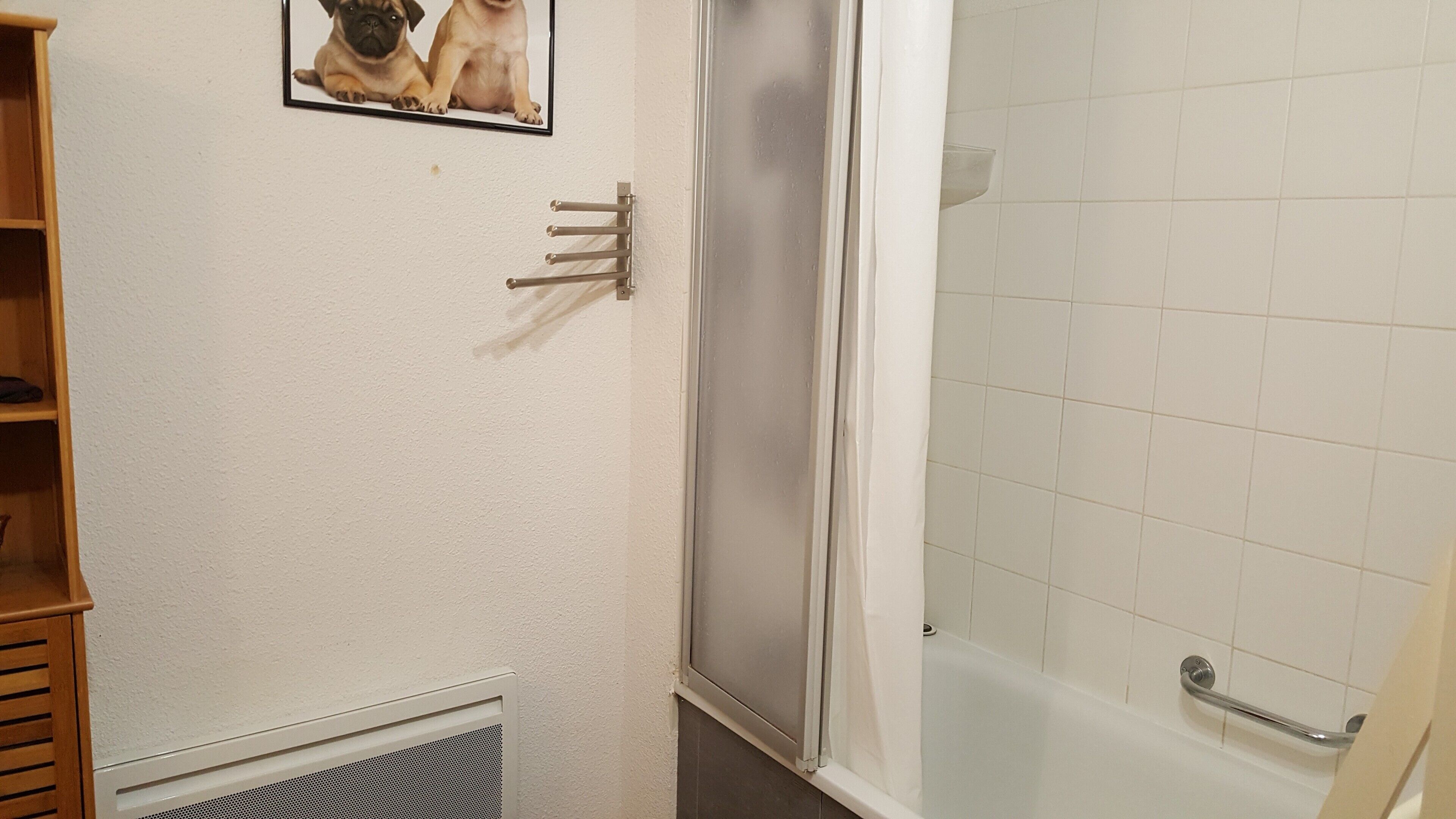 Ein Badezimmer mit Dusche, Toilette und einer kleinen Ablage mit einem Bilderrahmen.