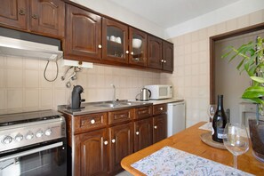 Une cuisine avec des meubles de rangement en bois, une cuisinière, un four à micro-ondes et un évier.