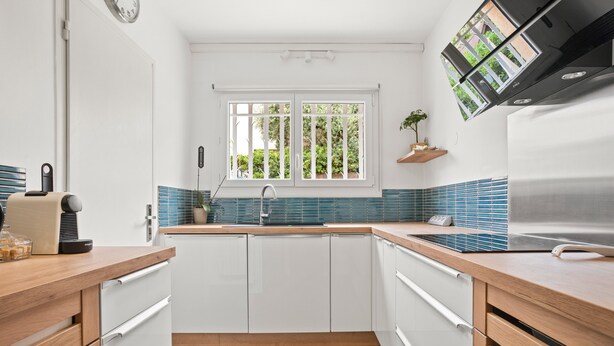 A modern kitchen with white cabinets, a wooden countertop, a built-in oven, and a window with a view of greenery. - Air-conditioned rental in Cogolin for 4–6 guests near St Tropez (Cogolin)