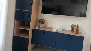A room with a TV mounted on the wall, a wooden cabinet with drawers, a small potted plant, and a tissue box. - Air-conditioned rental in Cogolin for 4–6 guests near St Tropez (Cogolin)
