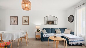 A modern living room with a sofa, a dining table, chairs, a lamp, and framed pictures on the wall. - Air-conditioned rental in Cogolin for 4–6 guests near St Tropez (Cogolin)