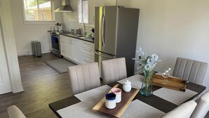 Une cuisine moderne avec un réfrigérateur en acier inoxydable, une table à manger avec un set de table et un vase rempli de fleurs.