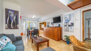A living room with a sofa, a coffee table, a TV, and a dining area with chairs and a table.