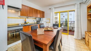 A kitchen with wooden cabinets, a stainless steel stove, and a dining table with chairs.