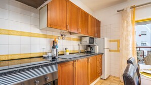 A kitchen with wooden cabinets, a gas stove, a microwave, and a refrigerator.