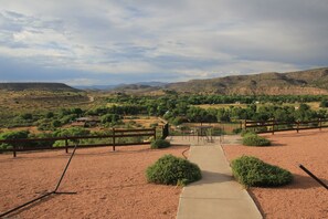 Stroll along the winding path to a serene seating area surrounded by lush vegetation and rolling hills.