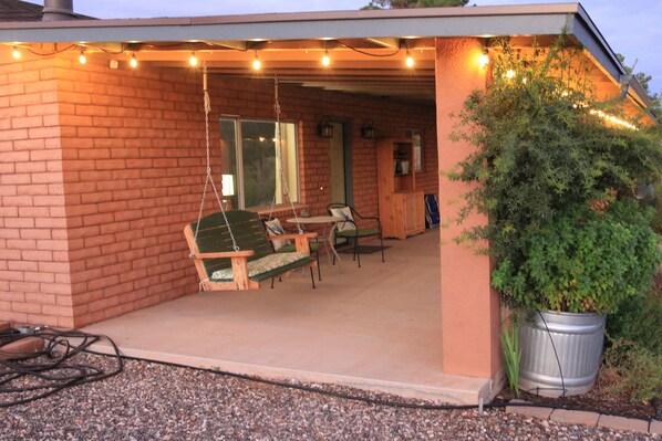 A covered patio with outdoor seating, a potted plant, and string lights.
