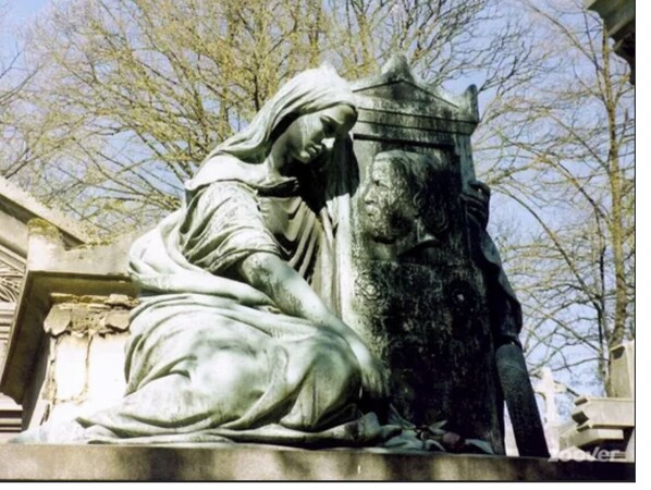 A statue of a woman and a man, possibly historical figures, in a garden setting with trees in the background. - Petit nid D'amour, au Coeur du Père Lachaise (Paris)