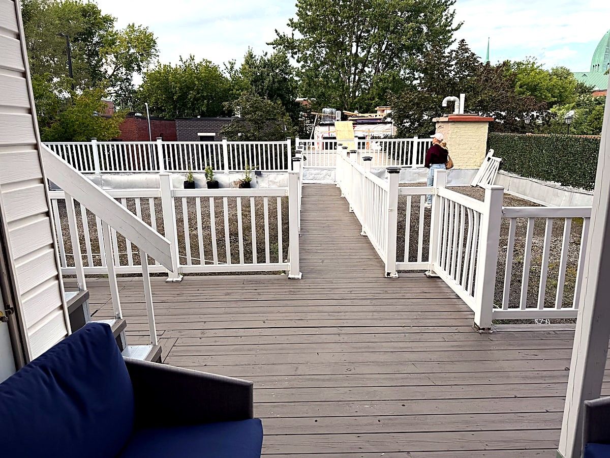 A wooden deck with white railings and a view of a building in the distance.