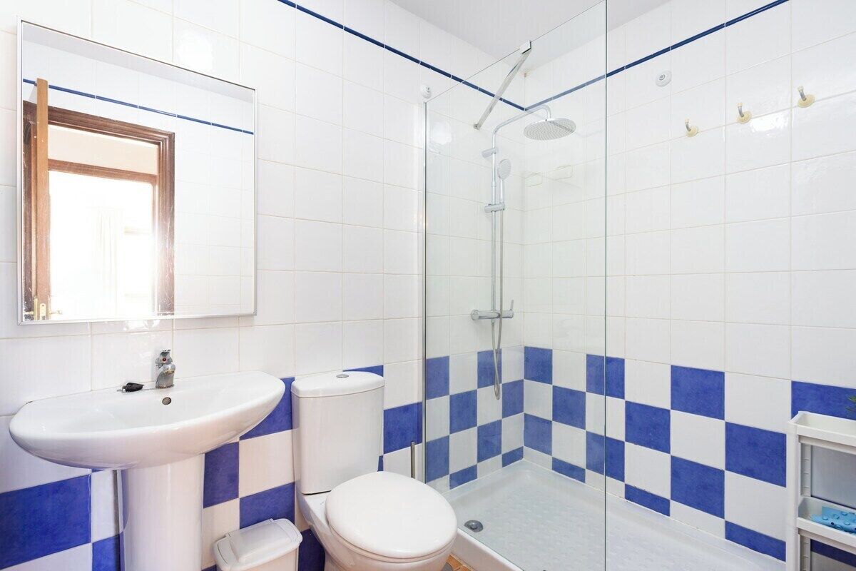 Une salle de bain avec une douche à parois de verre, un lavabo blanc et des toilettes.