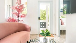 A modern living room with a pink sofa, a potted plant, and a TV mounted on the wall. - Siramada Village (Humacao)