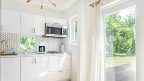 A modern kitchen with white cabinets, a microwave, a coffee maker, and a gas stove. - Siramada Village (Humacao)